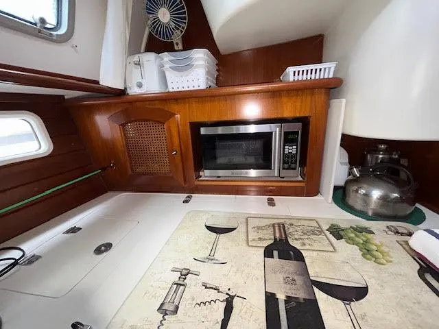 Walkabout Yacht Photos Pics Interior of 1997 Beneteau Oceanis 461 yacht kitchen with microwave and wine-themed decor.