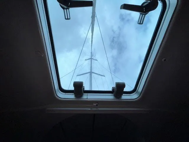Walkabout Yacht Photos Pics View through hatch of 1997 Beneteau Oceanis 461 sailboat, showing mast against cloudy sky.