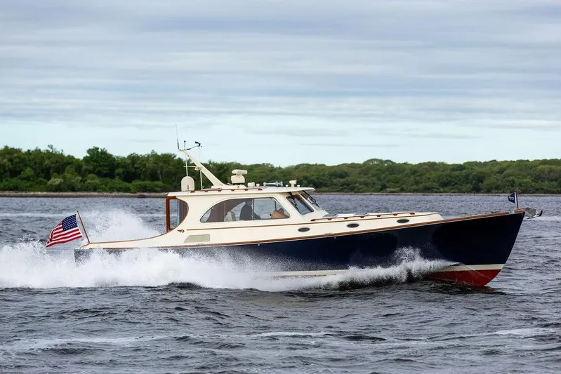 Carol Anne Yacht Photos Pics 2007 Hinckley Talaria 44 MY cruising on water with American flag, lush greenery in background.