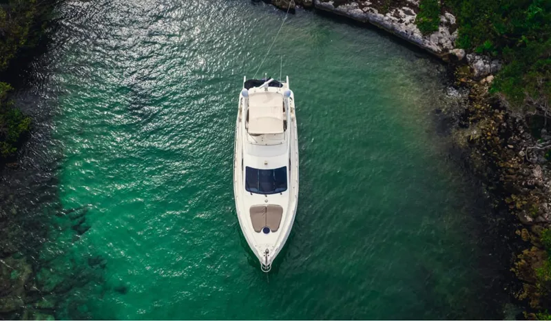 Belle Yacht Photos Pics Aerial view of 2004 Azimut 55E yacht in clear turquoise water, surrounded by rocky shoreline.