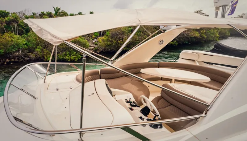 Belle Yacht Photos Pics Luxurious 2004 Azimut 55E yacht with elegant seating and canopy, docked near lush greenery.