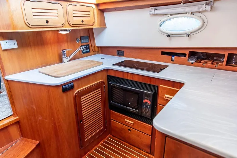 Mon Amour Yacht Photos Pics Hinckley Talaria 44 yacht kitchen interior, featuring wood cabinetry, countertop, stove, and microwave.