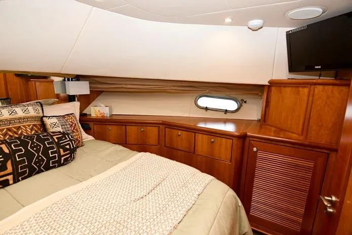  Yacht Photos Pics Luxurious bedroom in 2001 Symbol Raised Pilothouse Motoryacht with wood cabinetry and porthole window.