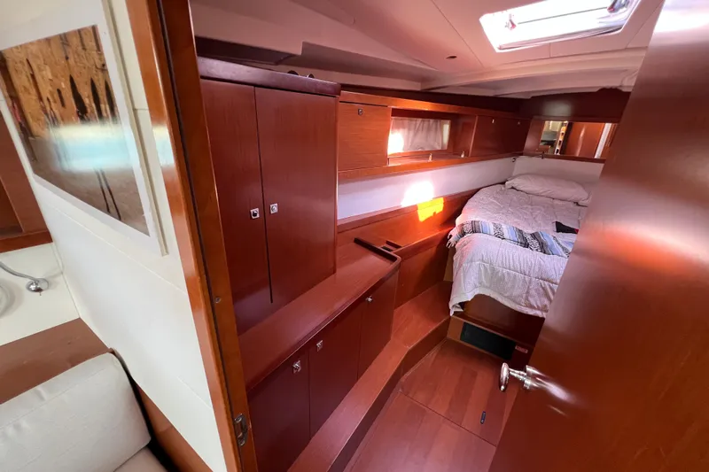 Adattare Yacht Photos Pics Interior cabin of 2012 Beneteau Oceanis 45 yacht with wooden furnishings and cozy bed.