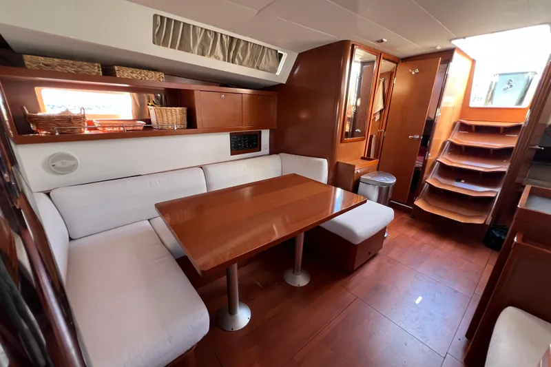 Adattare Yacht Photos Pics Interior of 2012 Beneteau Oceanis 45 yacht with wooden dining area and white seating.