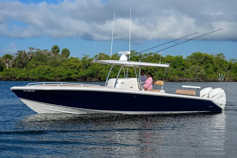  Yacht Photos Pics 2005 Venture 34 Center Console boat cruising on calm water with lush greenery background.