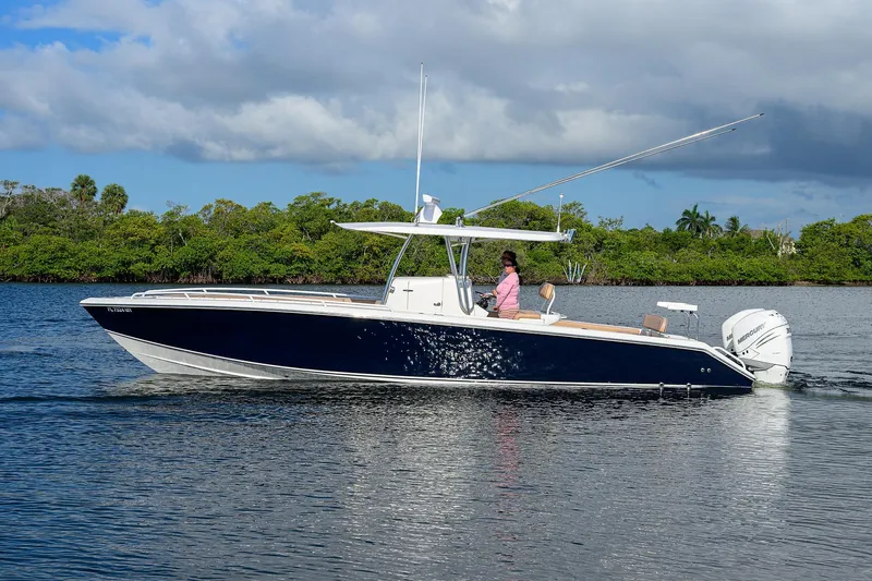  Yacht Photos Pics 2005 Venture 34 Center Console boat cruising on a calm river with lush greenery.
