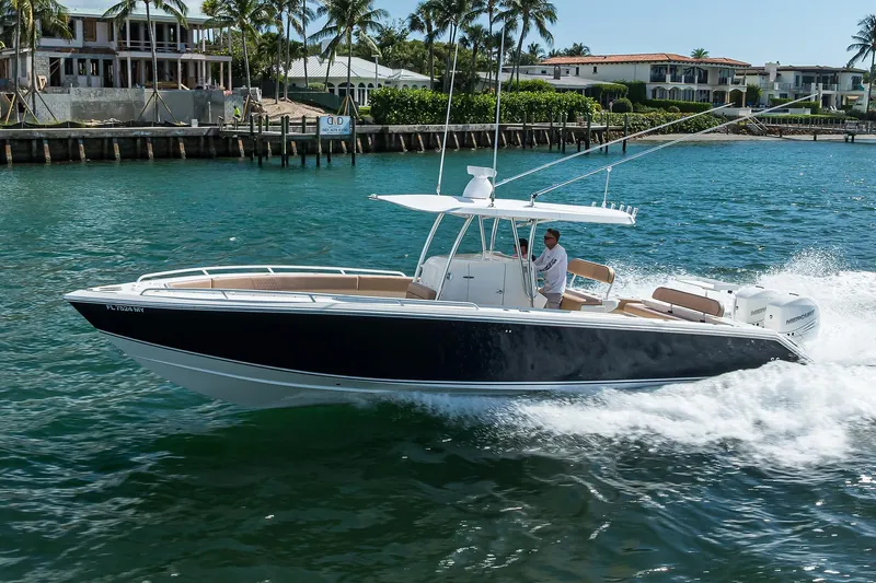  Yacht Photos Pics 2005 Venture 34 Center Console boat cruising on clear blue water near luxury homes.