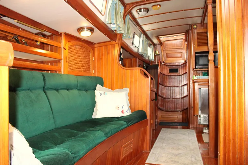 Divine Miss Em Yacht Photos Pics Cozy interior of 1990 Slocum 43 sailboat with green sofa and wooden paneling.