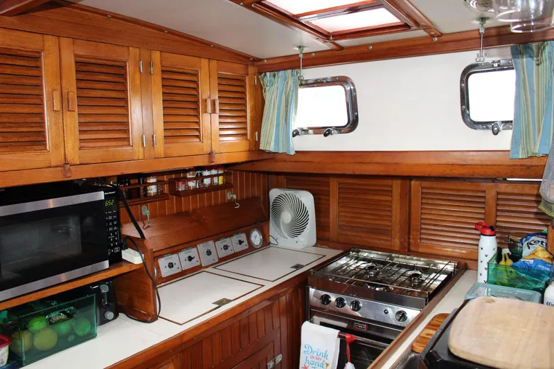 Divine Miss Em Yacht Photos Pics Cozy 1990 Slocum 43 yacht kitchen with wooden cabinets, stove, and microwave.