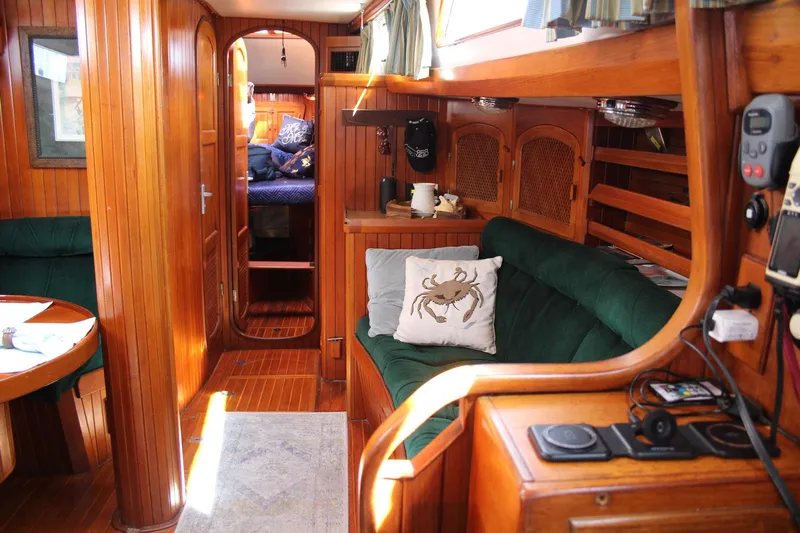 Divine Miss Em Yacht Photos Pics Cozy interior of a 1990 Slocum 43 sailboat with wooden paneling and green seating.