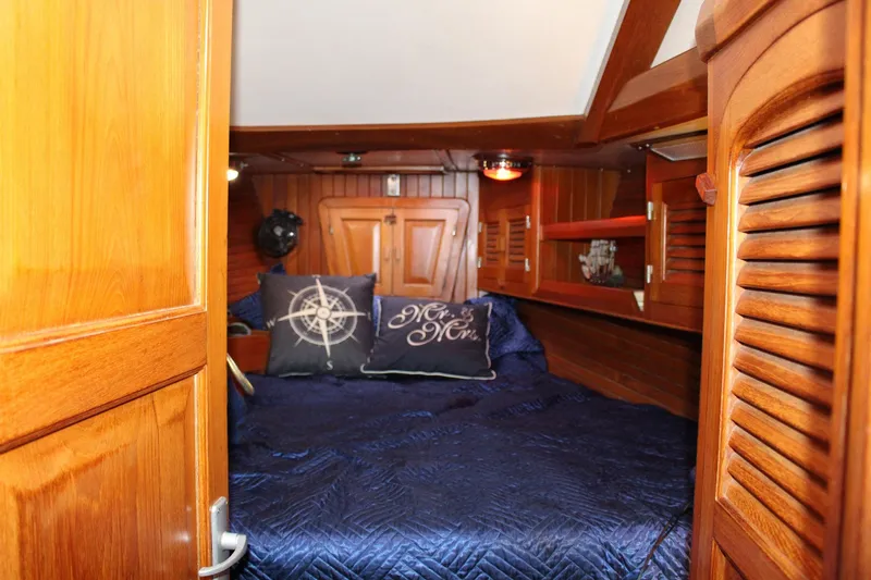 Divine Miss Em Yacht Photos Pics Cozy cabin interior of 1990 Slocum 43 sailboat with nautical-themed pillows and wooden finish.