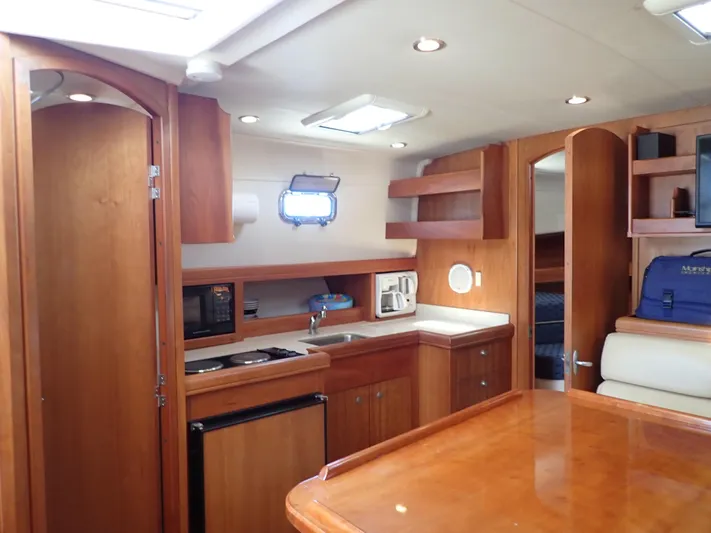  Yacht Photos Pics 2004 Mainship 34 Rum Runner II interior with wood cabinetry, kitchenette, and seating area.