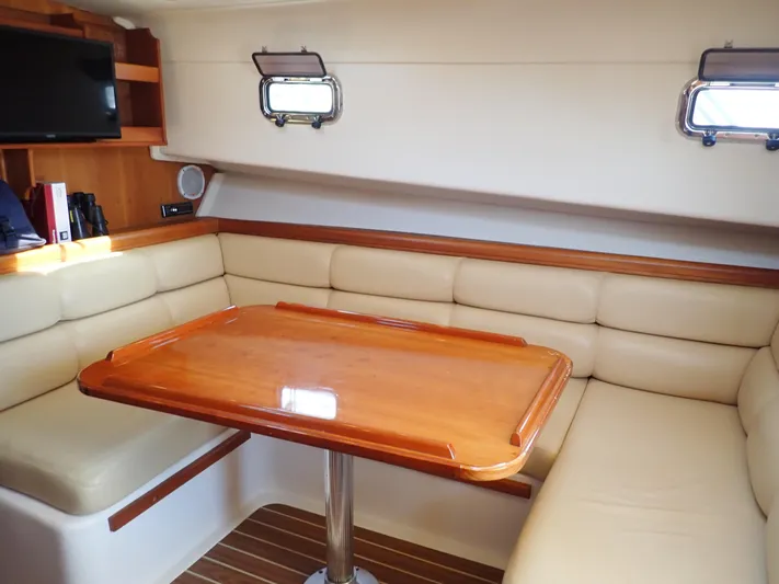  Yacht Photos Pics Interior of 2004 Mainship 34 Rum Runner II with beige seating and wooden table.