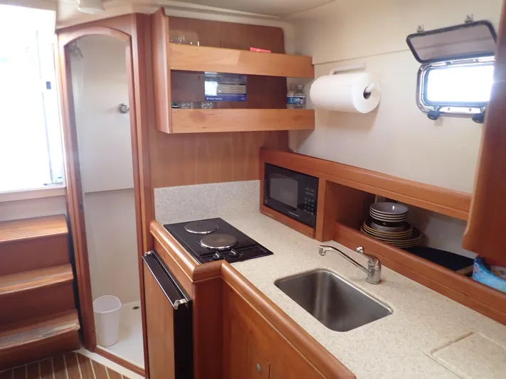  Yacht Photos Pics 2004 Mainship 34 Rum Runner II galley with stove, sink, microwave, and storage shelves.