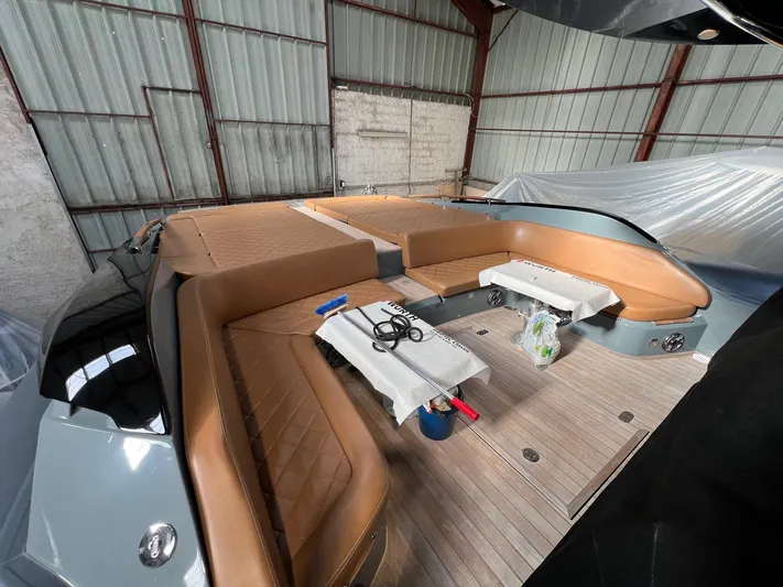 Stanislas Michel Yacht Photos Pics 2016 SACS Strider 18 boat interior with tan seating and wooden deck in a warehouse.