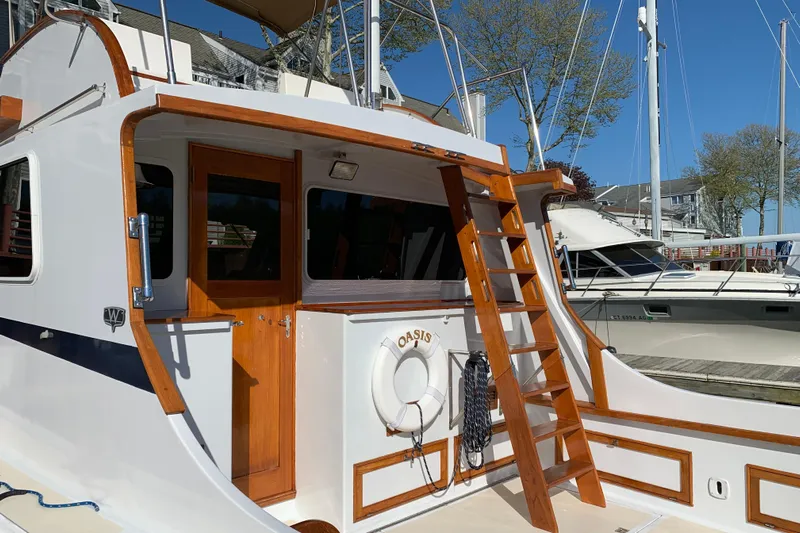 Oasis Yacht Photos Pics 1987 Wilbur 38 boat with wooden ladder and lifebuoy, docked at marina.