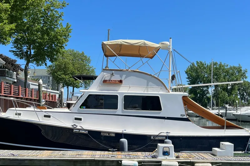Oasis Yacht Photos Pics 1987 Wilbur 38 boat docked, featuring a white cabin and tan canopy under a clear blue sky.