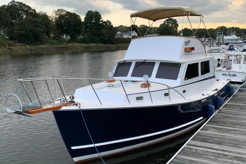 Oasis Yacht Photos Pics 1987 Wilbur 38 boat docked on calm water with trees in the background.