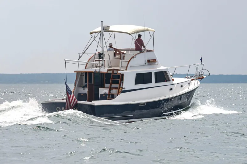 Oasis Yacht Photos Pics 1987 Wilbur 38 boat cruising on open water with American flag.
