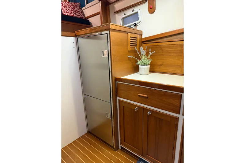 Oasis Yacht Photos Pics 1987 Wilbur 38 yacht interior with wooden cabinetry and stainless steel fridge.