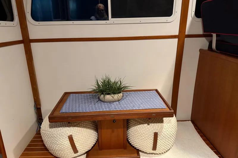 Oasis Yacht Photos Pics Interior of 1987 Wilbur 38 boat with table, plant, and poufs.