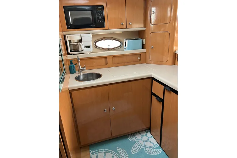 25 Knots Yacht Photos Pics 2001 Regal Commodore 3780 yacht kitchen with sink, microwave, and wooden cabinets.