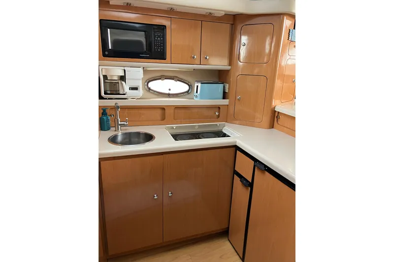 25 Knots Yacht Photos Pics 2001 Regal Commodore 3780 yacht kitchen with microwave, sink, and wooden cabinetry.