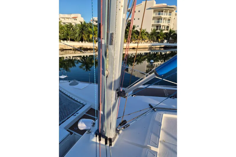 Chapter Two Yacht Photos Pics 2014 Lagoon 450 catamaran deck with mast and rigging, docked near palm trees and buildings.