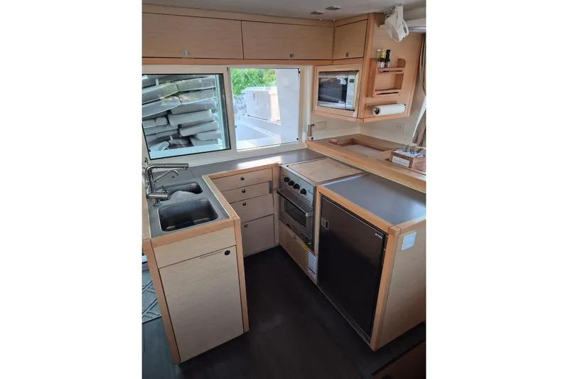 Chapter Two Yacht Photos Pics Modern kitchen interior of 2014 Lagoon 450 catamaran with appliances and wooden cabinetry.