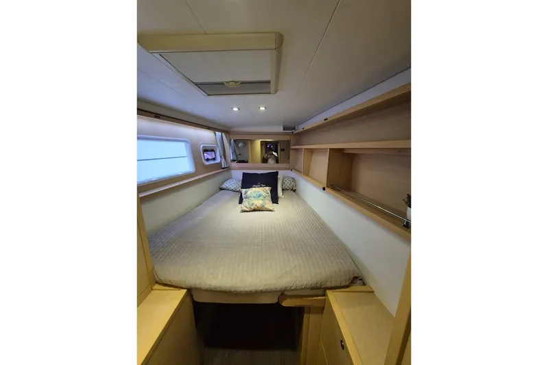 Chapter Two Yacht Photos Pics Interior cabin of 2014 Lagoon 450 yacht with cozy bed and wooden shelves.