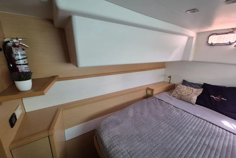 Chapter Two Yacht Photos Pics Cozy cabin interior of 2014 Lagoon 450 catamaran with bed, pillows, and fire extinguisher.
