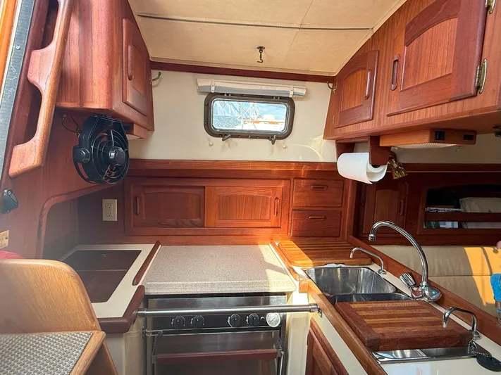 Dalliance Yacht Photos Pics Interior of 1993 Pacific Seacraft Crealock 34 sailboat, featuring a compact kitchen with wooden cabinetry.