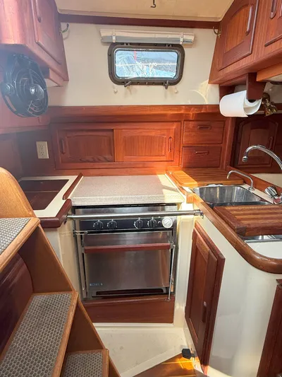 Dalliance Yacht Photos Pics Cozy 1993 Pacific Seacraft Crealock 34 yacht kitchen with wood cabinetry and stainless steel appliances.