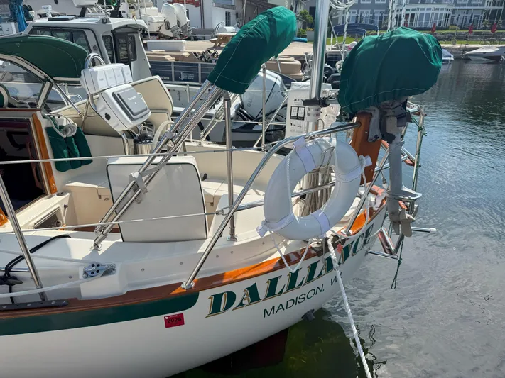 Dalliance Yacht Photos Pics 1993 Pacific Seacraft Crealock 34 sailboat docked, featuring green covers and a lifebuoy.