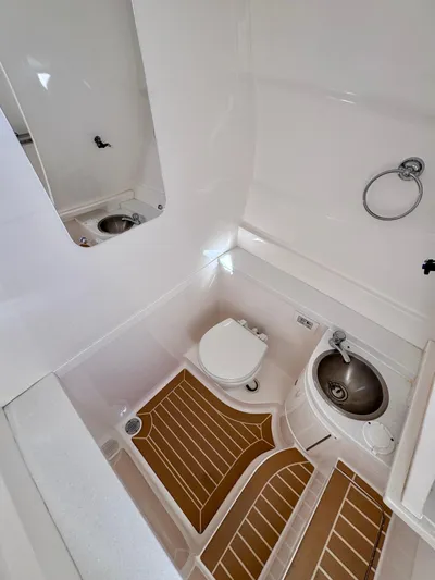 Herediterry Yacht Photos Pics 2017 Intrepid 375 FE boat bathroom with toilet, sink, and wooden floor mats.