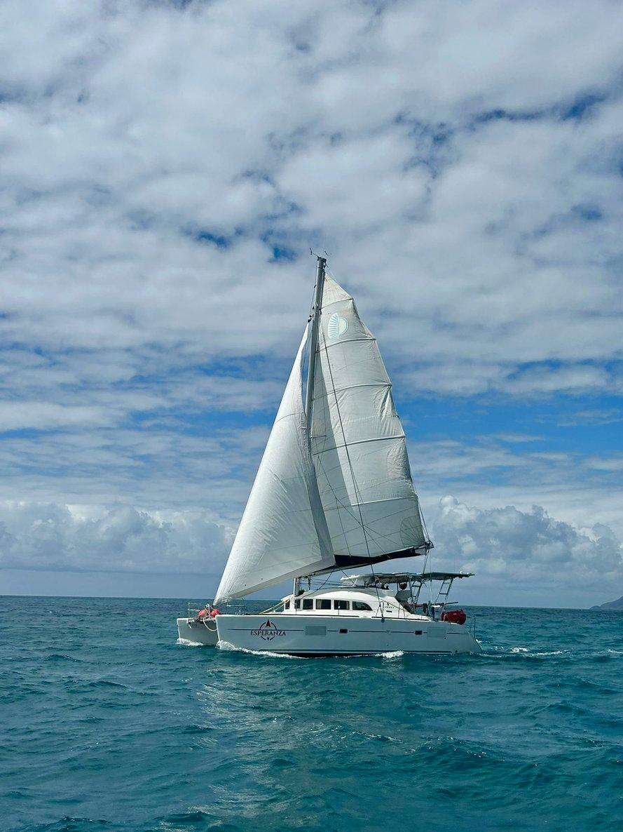 2019 Lagoon 380 S2 4/2 catamaran sailing on open ocean under cloudy sky.