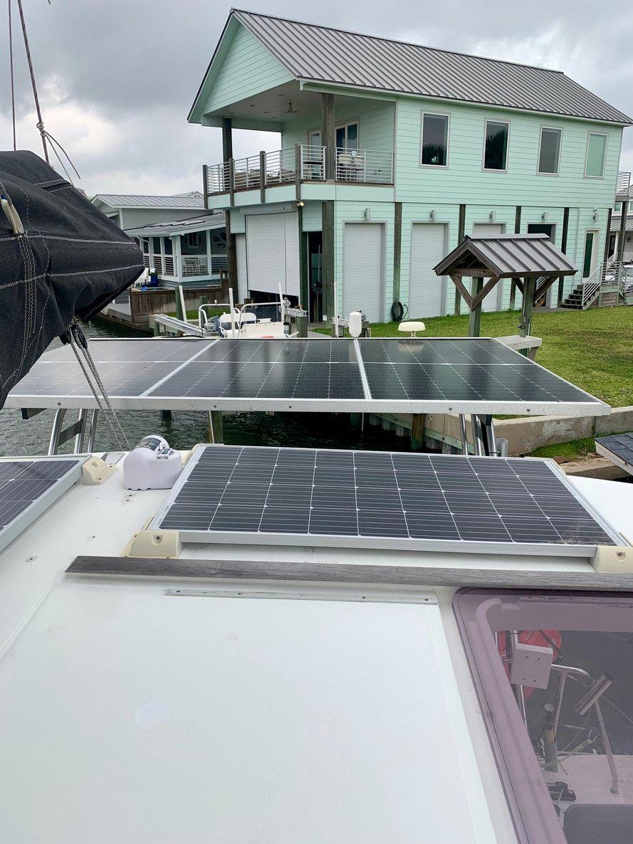 2019 Lagoon 380 S2 4/2 catamaran with solar panels, docked near a modern house.