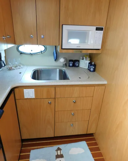 Cap & Dan Yacht Photos Pics 2001 Tiara Yachts 3800 Open kitchen with sink, microwave, and wooden cabinetry.