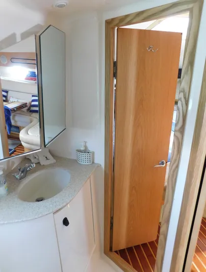 Cap & Dan Yacht Photos Pics 2001 Tiara Yachts 3800 Open bathroom with sink, mirror, and wooden door.