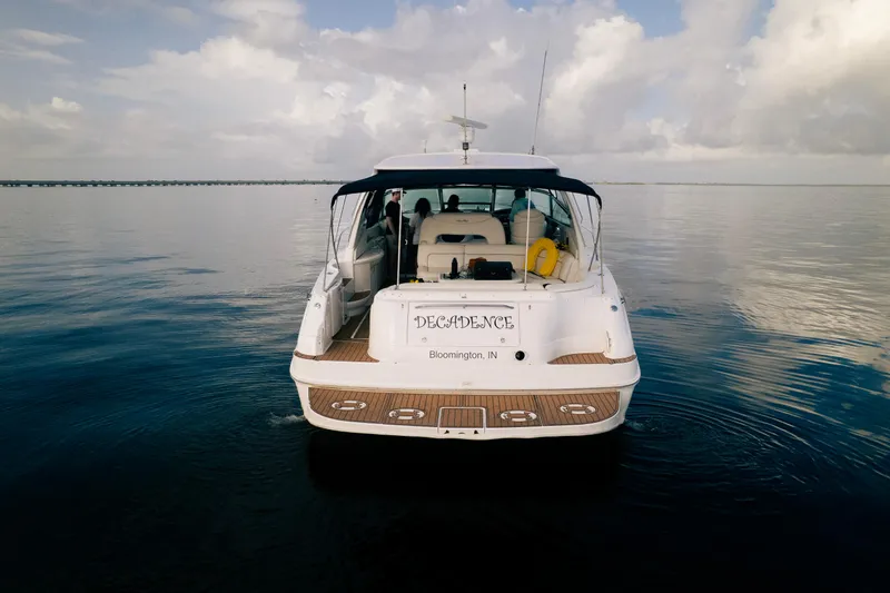 Decadance Yacht Photos Pics 2003 Sea Ray 460 Sundancer yacht on calm water, rear view, under cloudy sky.
