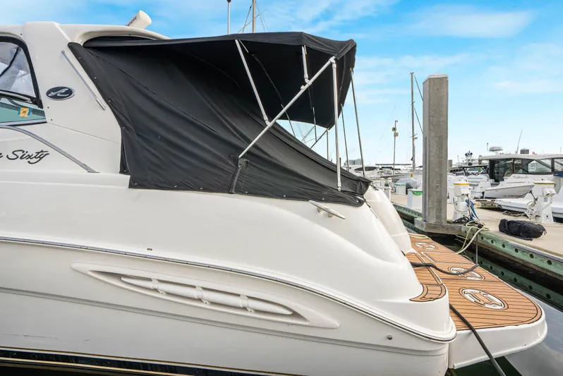 Decadance Yacht Photos Pics 2003 Sea Ray 460 Sundancer yacht docked with black canopy, wooden deck, and marina background.