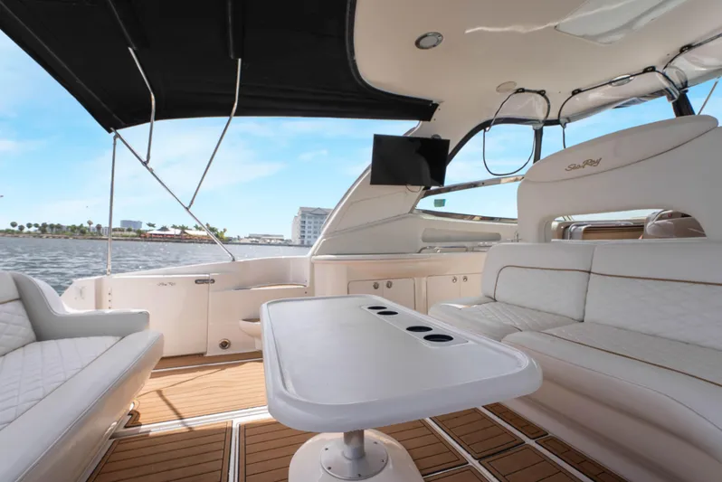Decadance Yacht Photos Pics 2003 Sea Ray 460 Sundancer yacht interior with white seating and table, under black canopy.