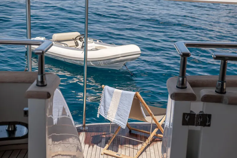 Easy Yacht Photos Pics Sanlorenzo 82 yacht deck with chair, towel, and inflatable boat on the water, 2009 model.