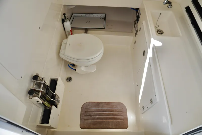 Vasea Yacht Photos Pics 2021 Boston Whaler 330 Outrage boat bathroom with toilet, sink, and storage compartments.