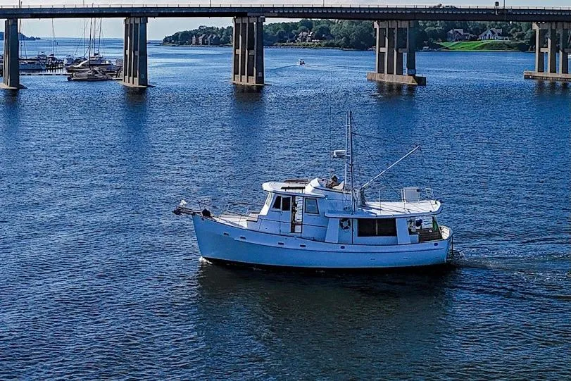 1983 Kadey-Krogen Krogen 42 Trawler cruising under a bridge on a sunny day.