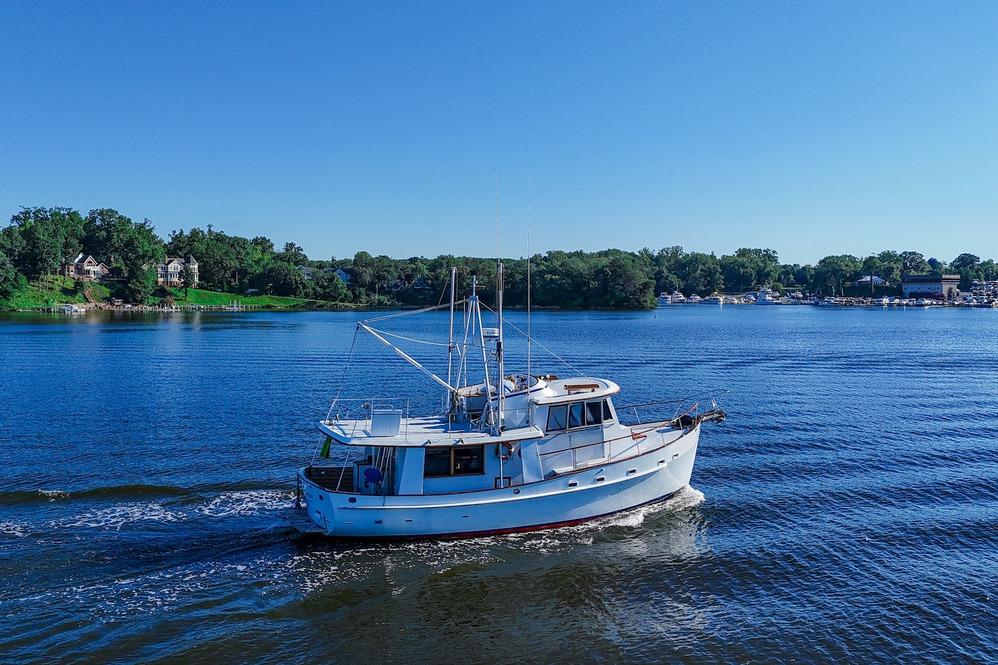 1983 Kadey-Krogen Krogen 42 Trawler cruising on a serene lake under clear blue skies.