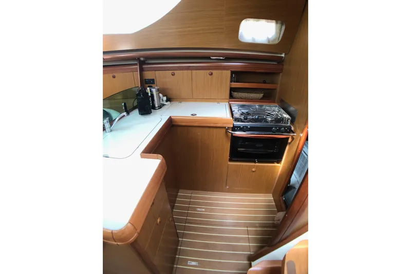 Marine Services S.a.s. Di Berruto Claudia Yacht Photos Pics 2006 Jeanneau Sun Odyssey 42 DS yacht kitchen with stove, sink, and wooden cabinetry.