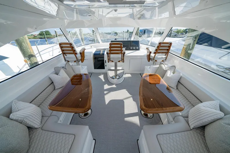 Pamela Yacht Photos Pics Luxurious interior of 2024 Viking 48 Sport Tower yacht with elegant seating and wooden tables.