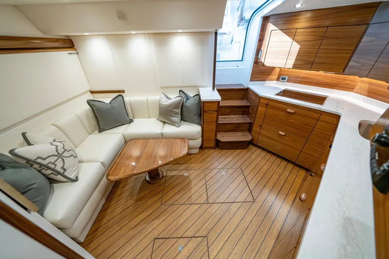 Pamela Yacht Photos Pics Luxurious interior of 2024 Viking 48 Sport Tower yacht with elegant wood finish and cozy seating.